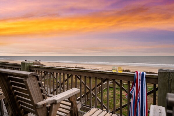 A wooden deck with a view of the beach and ocean during sunset. - Gulf Front ~ Hot Tub ~ Mini Golf ~ Mini Pickleball ~ Bocce Court ~ NO BUNKS (Bolivar Peninsula)