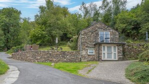 A stone house with a balcony, a small porch, and a stone wall. - Romantic getaway, little two bed, two bath barn conversion with amazing views & parking (Ambleside)