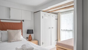 A bedroom with a bed, a wardrobe, a nightstand, a lamp, and a window with curtains. - Romantic getaway, little two bed, two bath barn conversion with amazing views & parking (Ambleside)