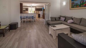 A modern living room with a sofa, coffee table, and dining area. - Holiday apartment on the quiet (Vrbnik)