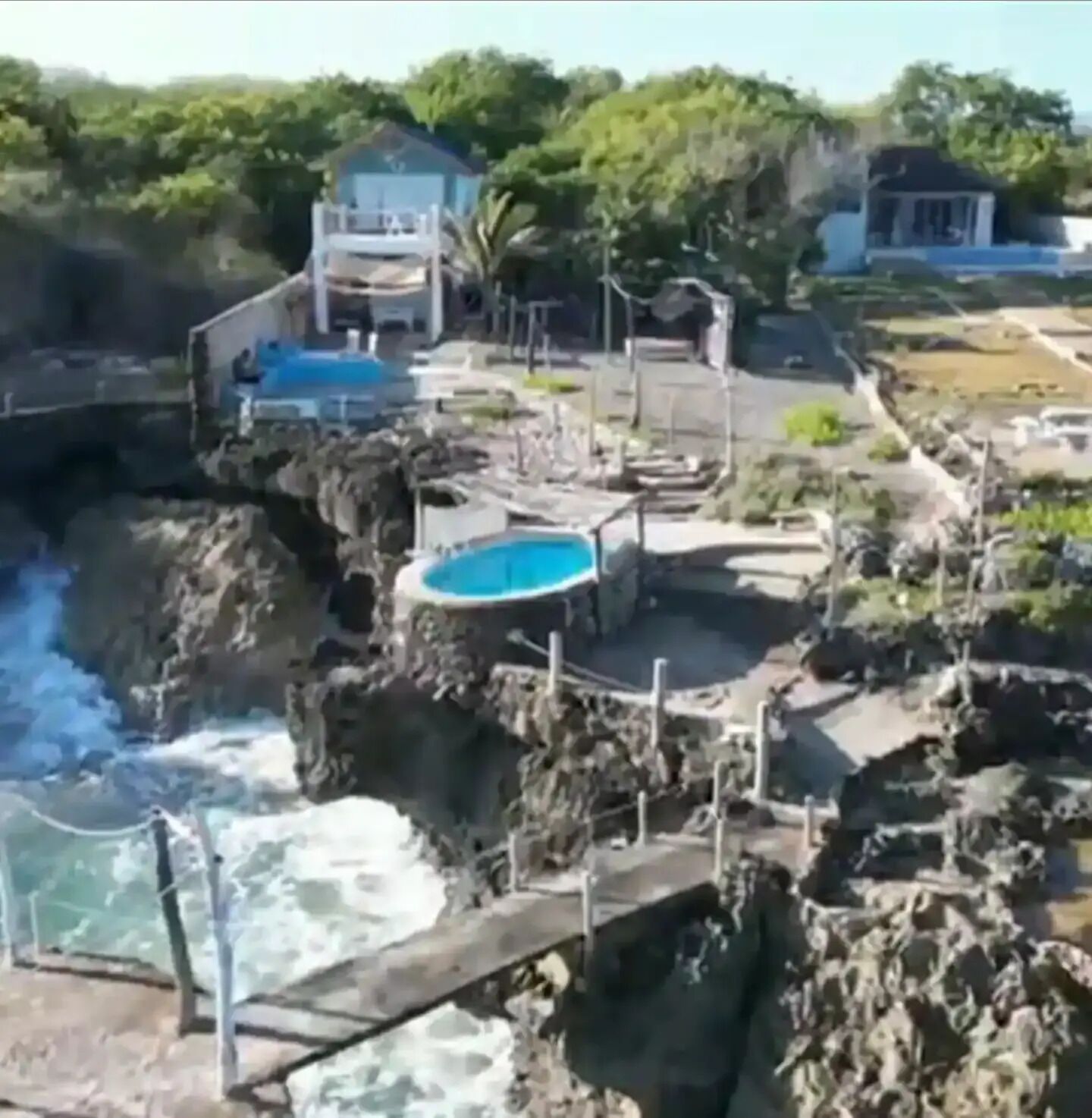 Una zona costera con costa rocosa, una pequeña piscina y un edificio con techo azul.