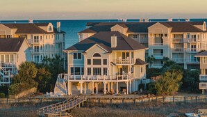 A beachfront property with multiple houses, a covered deck, and a small dock. - Paradise Found: Waterfront Escape with Dock, Firepit, and Sunsets Galore! (Wrightsville Beach)
