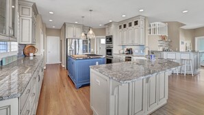 A spacious kitchen with granite countertops, a central island, and modern cabinetry. - Paradise Found: Waterfront Escape with Dock, Firepit, and Sunsets Galore! (Wrightsville Beach)