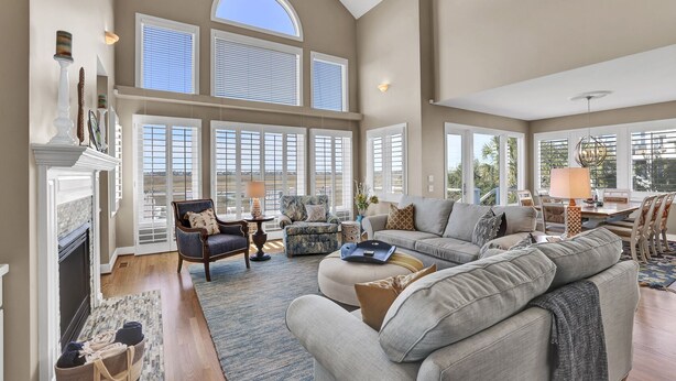 A spacious living room with a fireplace, large windows, and a high ceiling. - Paradise Found: Waterfront Escape with Dock, Firepit, and Sunsets Galore! (Wrightsville Beach)