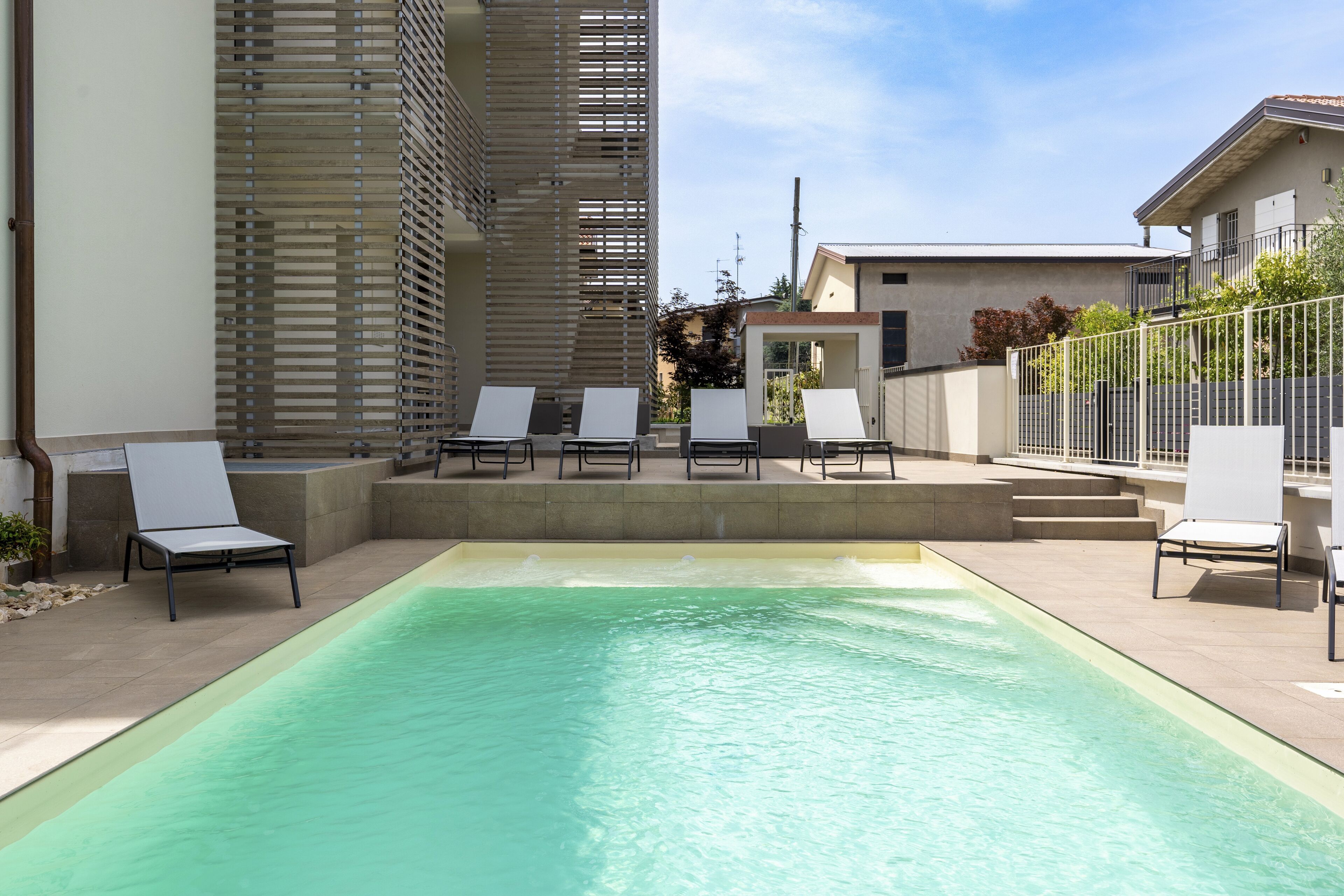 Una piscina con sillas de descanso y un edificio moderno al fondo.