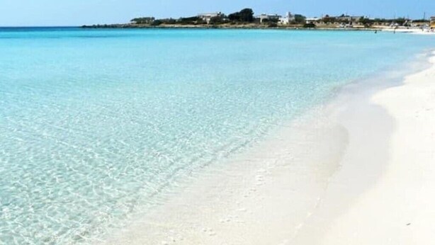 Ein Strand mit klarem türkisblauem Wasser und weißem Sand.