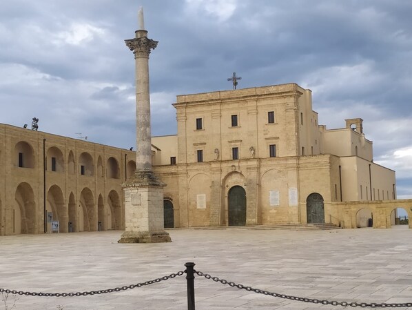 Un edificio histórico con una columna central y arcos, rodeado de un patio empedrado.