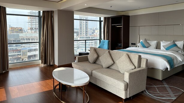 Ein modernes Hotelzimmer mit einem großen Bett, einer Couch und einem kleinen Tisch.