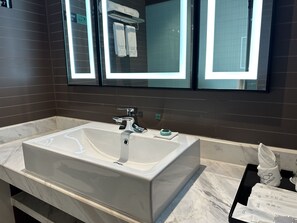 Une salle de bain moderne avec un grand lavabo blanc, un robinet chromé et un miroir au-dessus.