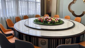 Ein Konferenzraum mit rundem Tisch, orangefarbenen Stühlen und einer floralen Tischdekoration.