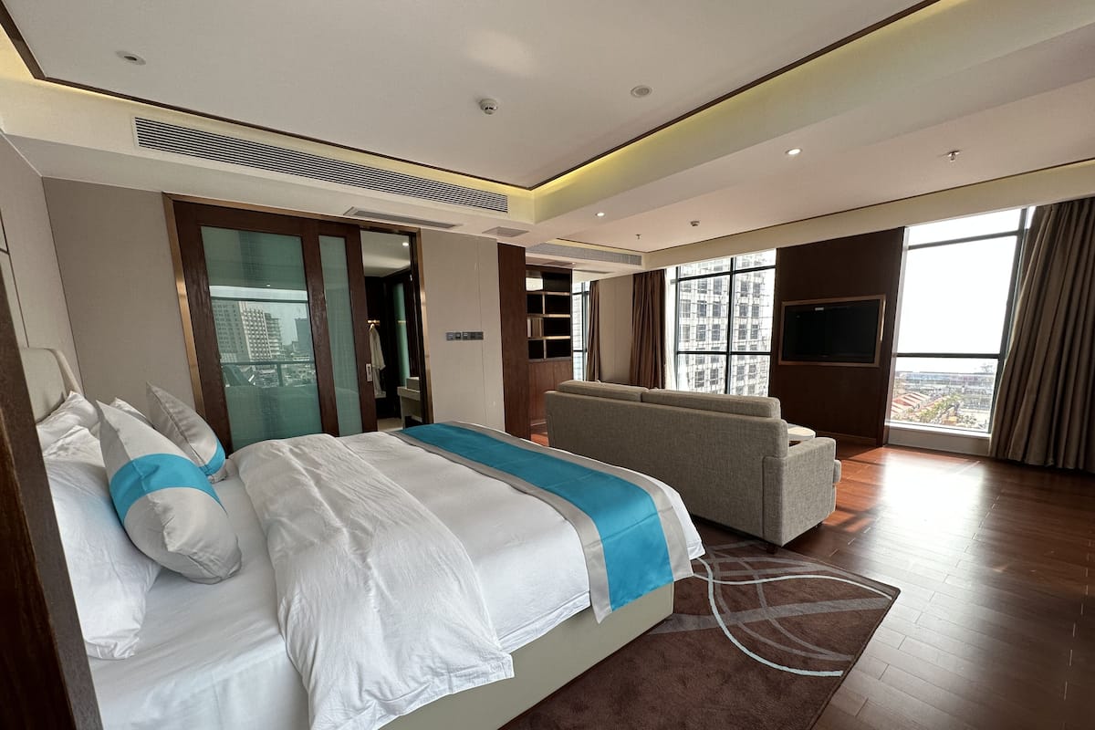 Un hotel moderno con una cama grande, un sofá, un televisor y vistas a la ciudad.
