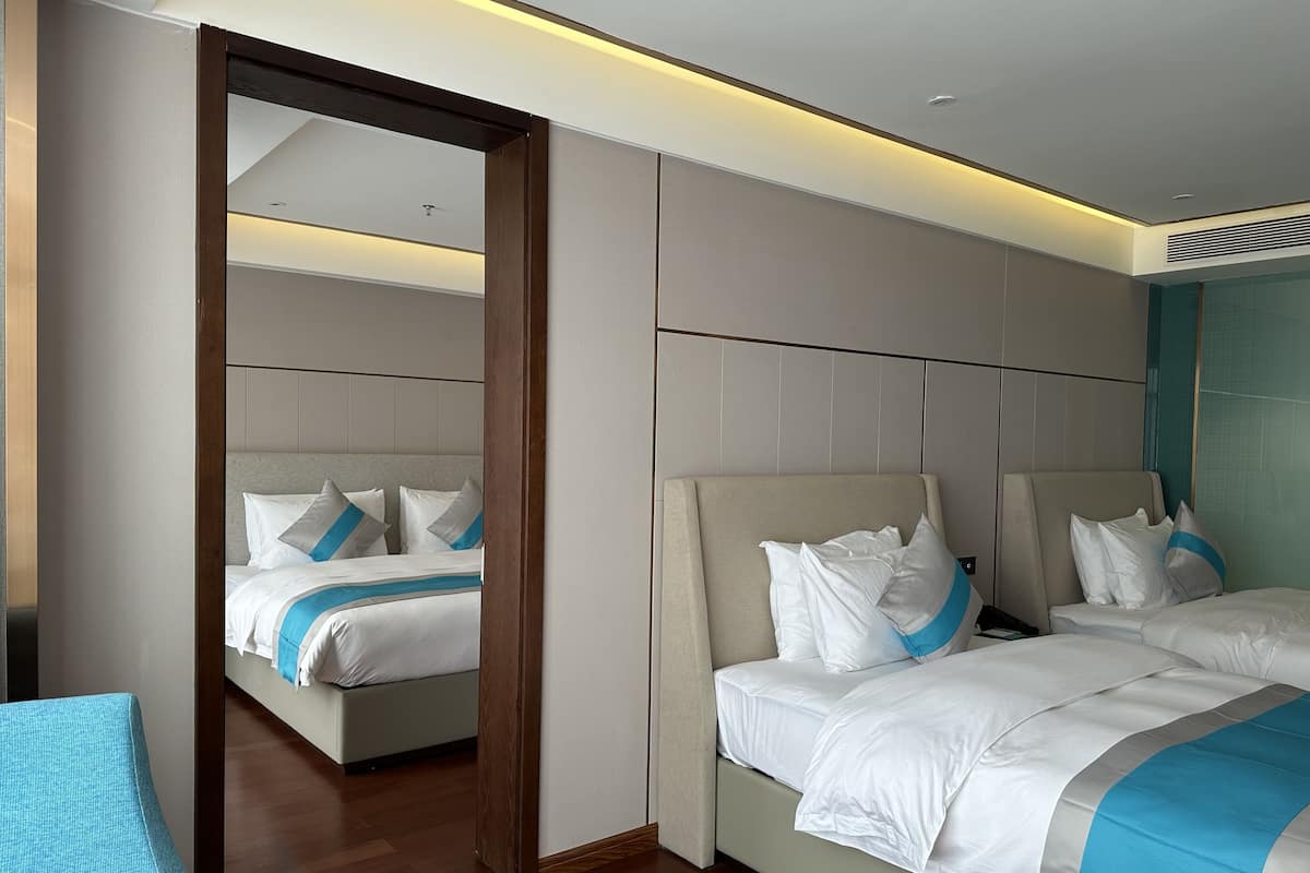 Una habitación de hotel moderna con dos camas, un espejo grande y suelo de madera.
