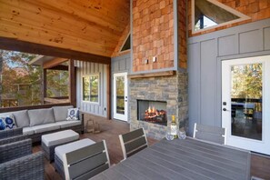 A covered outdoor seating area with a stone fireplace, wooden ceiling, and a view of the surrounding trees. - Luxury Mountain Escape - Dog-Friendly- Fenced Yard Freedom (Ellijay)