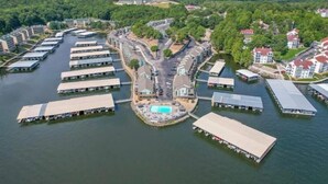 An aerial view of a waterfront property with multiple docked boats, a central swimming pool, and surrounding residential buildings. - Condo with Indoor Pool and Hot Tub! (Village of Four Seasons)