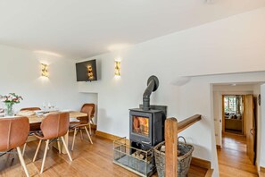A dining area with a table set for four, a wood-burning stove, and a TV mounted on the wall.