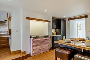 A modern kitchen with a built-in stove, wooden cabinets, and a dining area with a wooden table and leather seating.