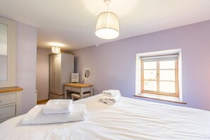 Un dormitorio con cama, tocador con espejo, armario y ventana con luz diurna.