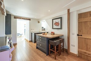 A modern kitchen with a wooden island, dark cabinetry, and a wooden door.