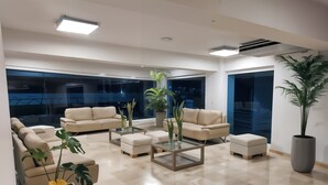 Ein stilvolles Wohnzimmer mit beigen Sofas, einem Glastisch und Zimmerpflanzen.