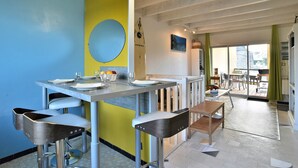 Un comedor moderno con barra, taburetes y una mesa dispuesta para dos personas.