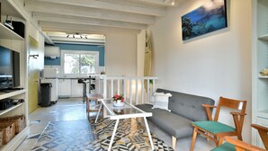 Una sala de estar moderna con un sofá, sillas, una mesita de centro y una cocina al fondo.