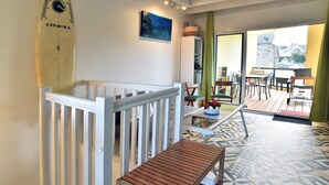 Una habitación con un banco de madera, una tabla de surf, un cuadro y vistas al exterior.