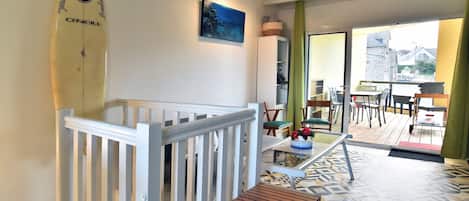 A room with a wooden bench, a surfboard, a painting, and a view of the outside.
