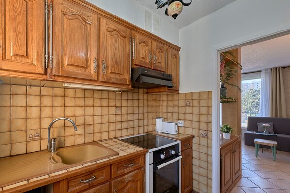 Une cuisine avec des meubles de rangement en bois, un évier, une cuisinière et un grille-pain.