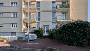 Ein mehrstöckiges Wohnhaus mit Balkonen, einem überdachten Eingangsbereich und einem gepflegten Garten.