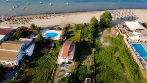 Vista aérea de una propiedad costera con piscina, sombrillas de playa y embarcaciones.