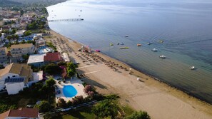 Vue aérienne d’une zone côtière avec une plage, une jetée et une piscine.