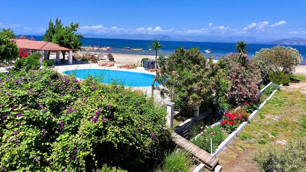 Un complejo turístico con piscina, sillas de playa y vista al mar.
