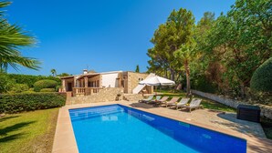 A swimming pool with lounge chairs and umbrellas, surrounded by a stone house and lush greenery. - Villa Victoria Alcudia Alcudia Bonaire for 6 with pool (Alcúdia)