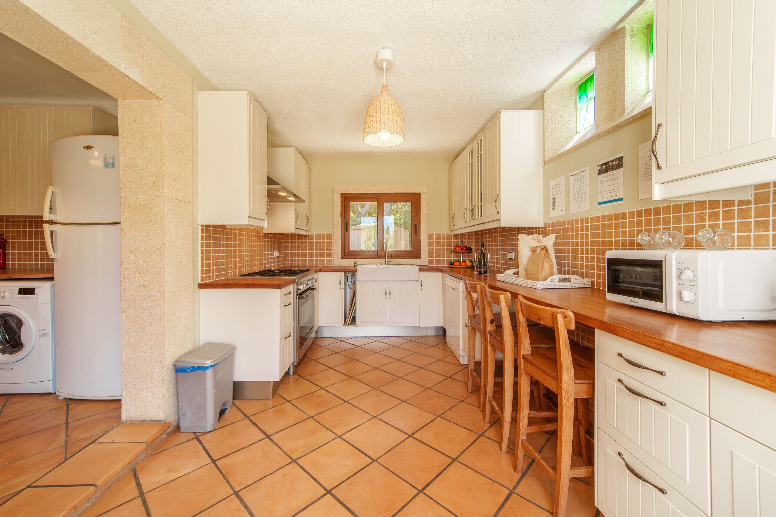 A kitchen with white cabinets, a microwave, a sink, and a window.