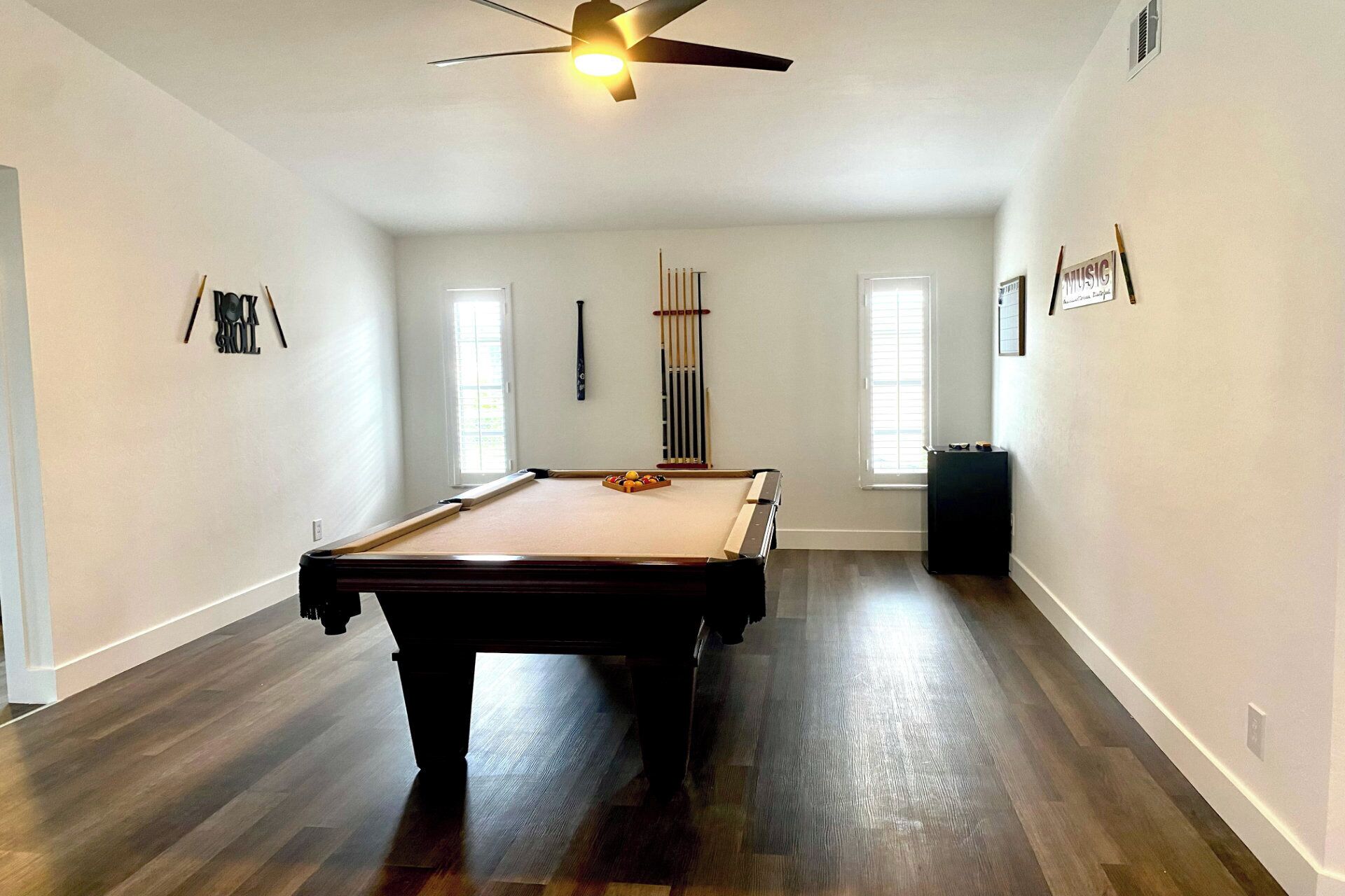 A spacious room with a pool table, a ceiling fan, and a billiards rack.