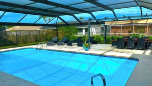 A swimming pool with a glass ceiling, surrounded by lounge chairs and potted plants. - VRCC Villa The Rocks - where luxury meets beauty (Cape Coral)