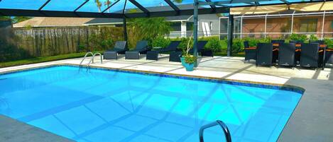 En swimmingpool med et glastag, omgivet af liggestole og krukkeplanter.