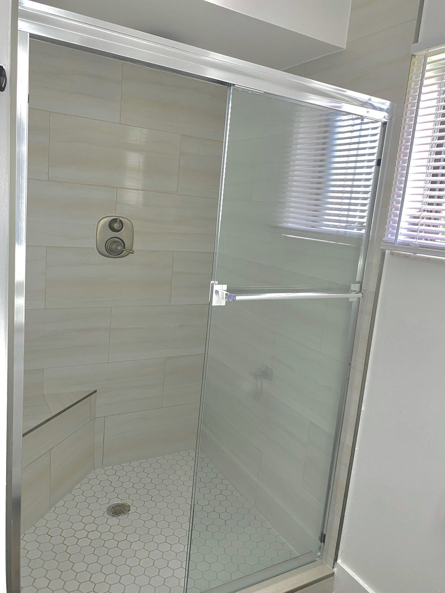 A glass-enclosed shower with a tiled floor.