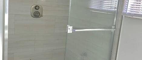 A glass-enclosed shower with a tiled floor.