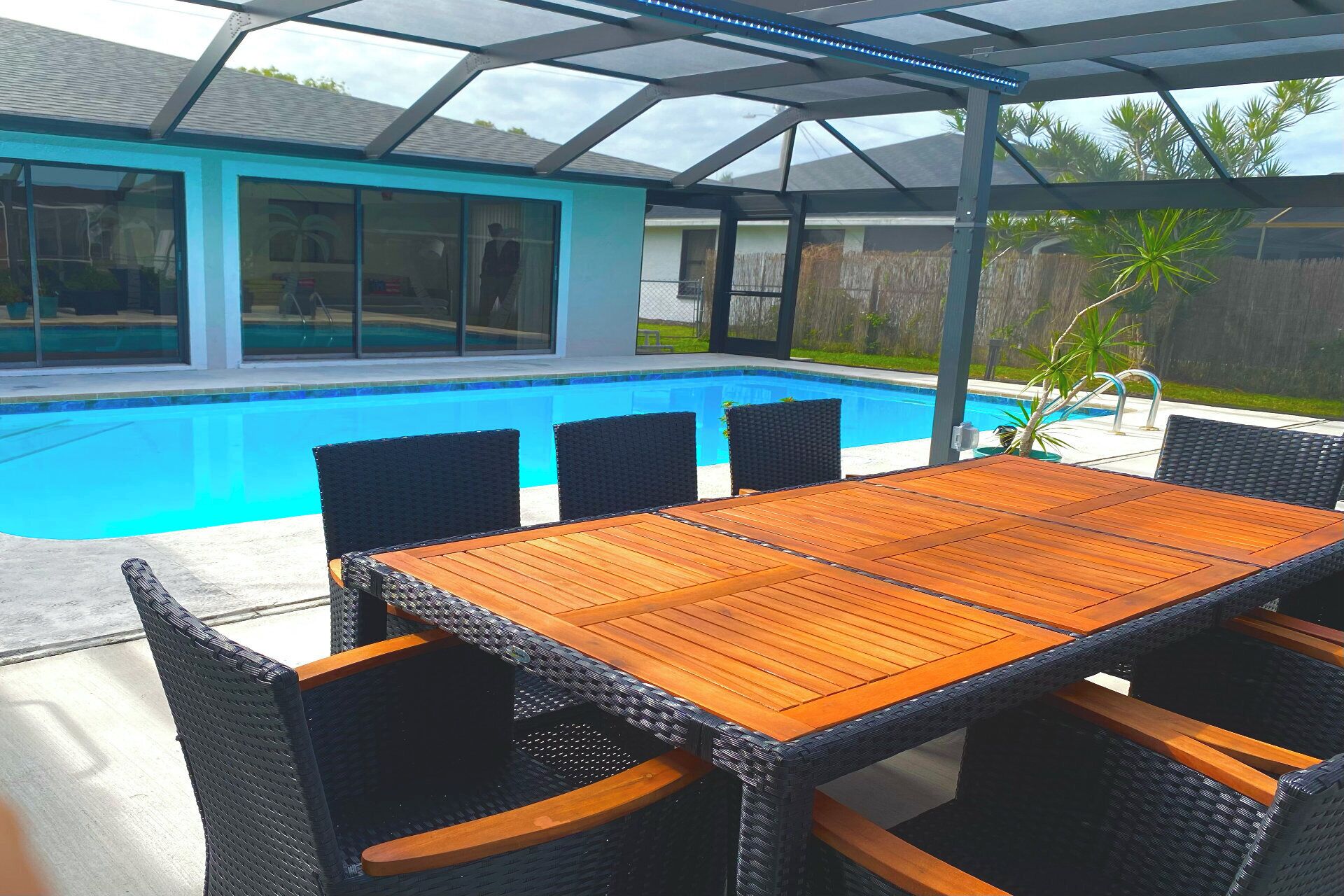 A covered patio with a pool, outdoor furniture, and a view of a house.