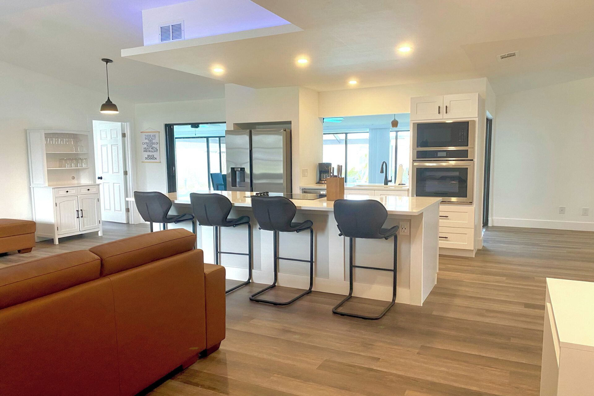 A modern kitchen with a central island, bar stools, and built-in appliances.
