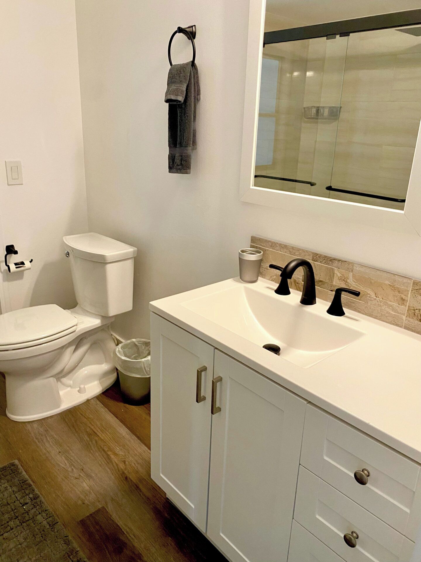 A bathroom with a white toilet, a sink with black faucets, and a mirror above the sink.