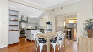 Una cucina compatta con mobili bianchi, un'isola centrale e un'area pranzo con sedie bianche.