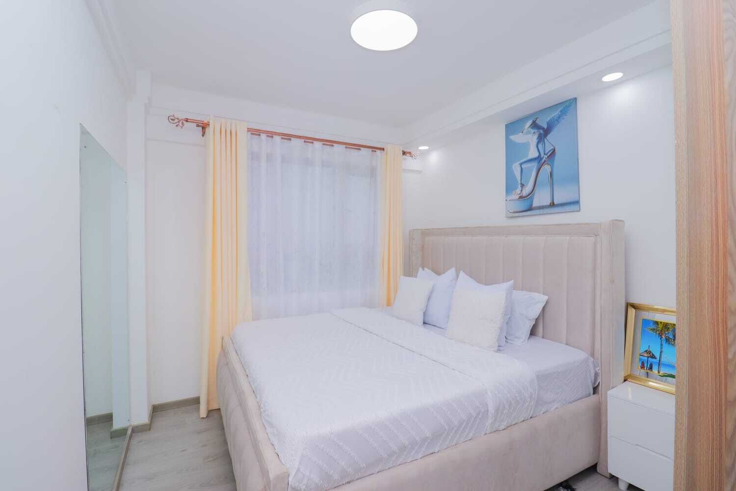 A bedroom with a bed, curtains, a nightstand, and a painting on the wall.