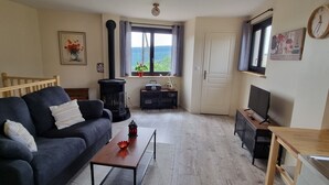 Een gezellige woonkamer met een bank, een salontafel, een televisie, een open haard en een raam met uitzicht.