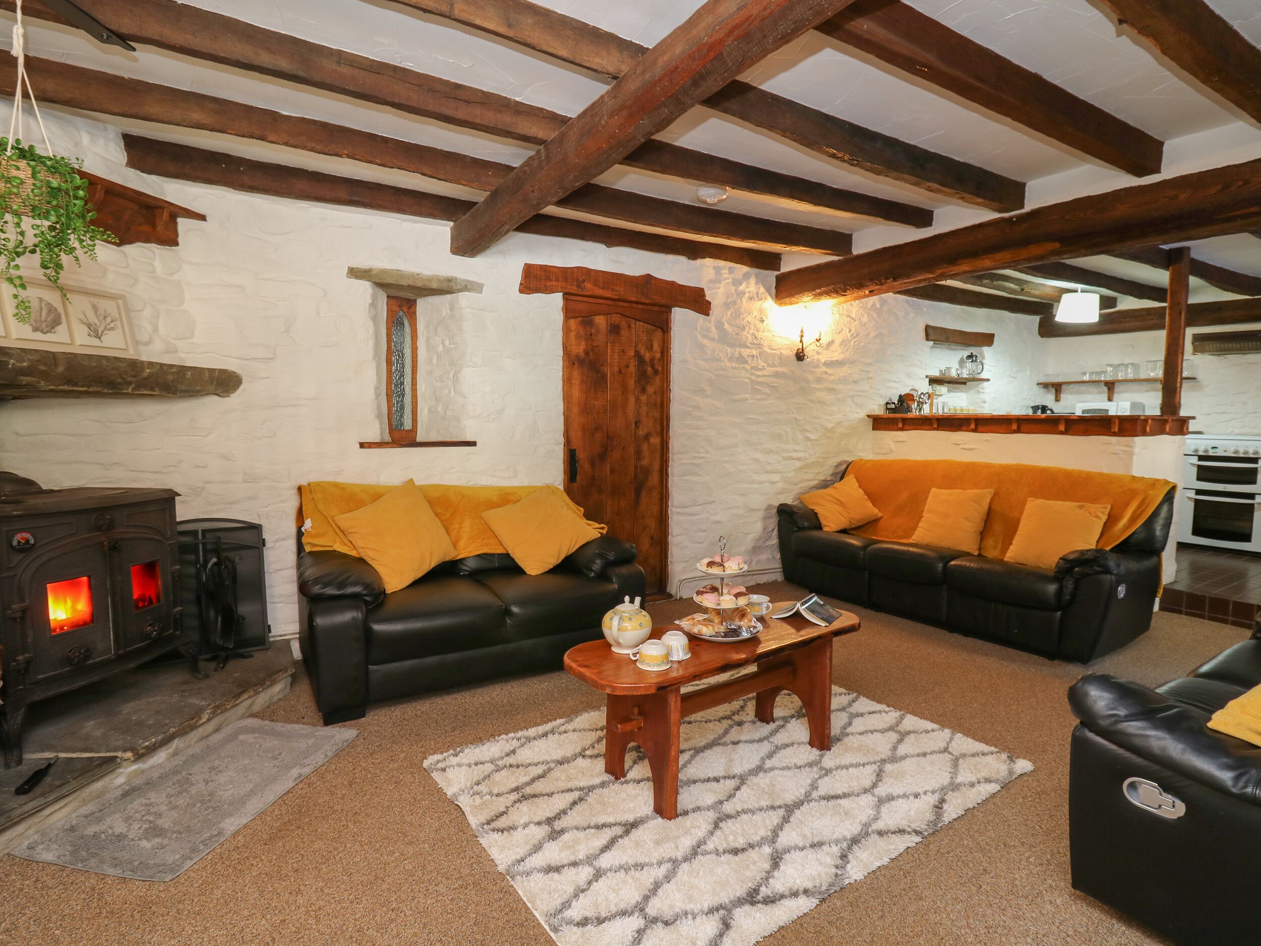 A cozy living room with two black leather sofas, a wooden coffee table, and a stone fireplace.