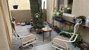 A patio with two rocking chairs, a small table, and various potted plants.