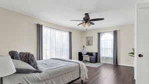 A bedroom with a bed, a desk, a ceiling fan, and large windows. - Entire Furnished rental unit in San Antonio, Texas

 (San Antonio)