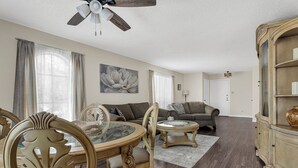 A living room with a dining table, two sofas, a chandelier, and a large window with curtains. - Entire Furnished rental unit in San Antonio, Texas

 (San Antonio)