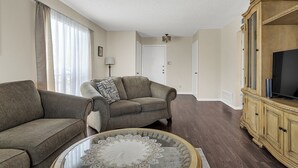 A living room with two sofas, a coffee table, a TV on a wooden cabinet, and a door in the background. - Entire Furnished rental unit in San Antonio, Texas

 (San Antonio)